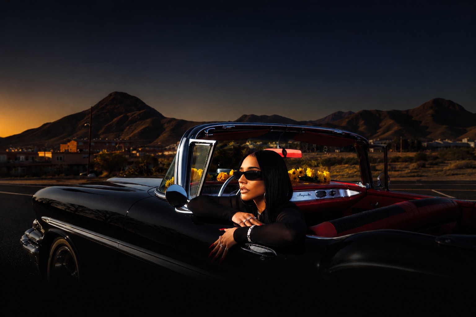 Krystall Poppin resting on the door of a vintage black convertible at dusk, mountains in the distance